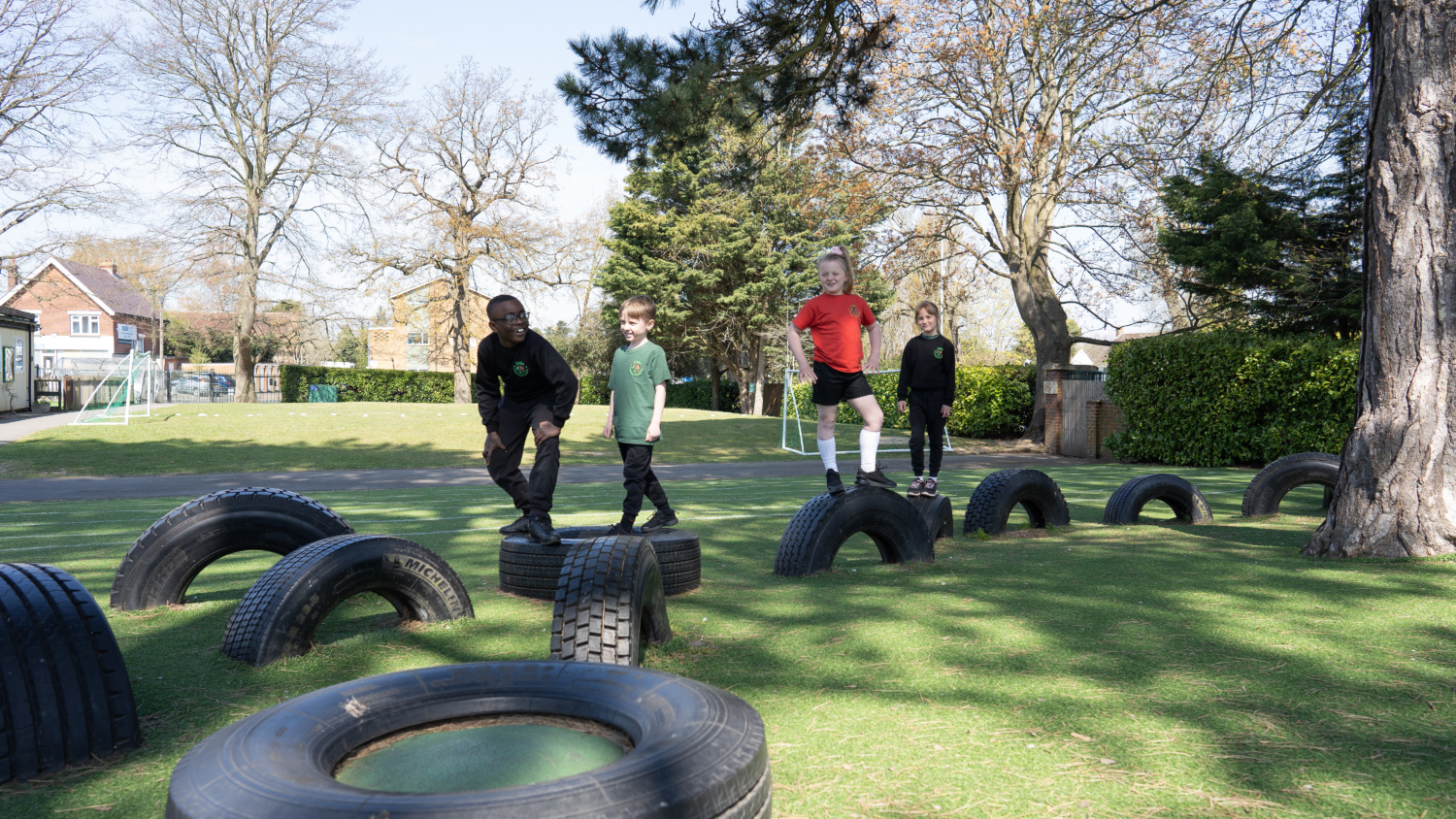 Four children playing on tyres in the school playground